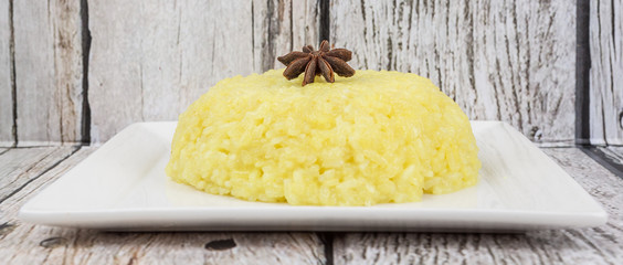 Malaysian dish Yellow Glutinous Rice or locally known as Pulut Kuning on white plate over wooden background