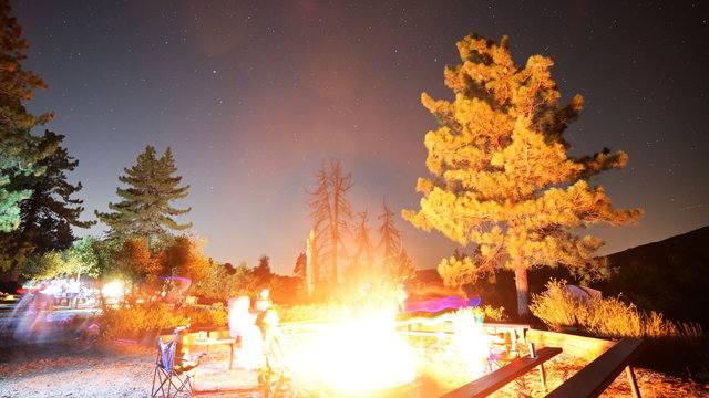 Time lapse footage with pan left motion of a group of campers surrounding bonfire in alpine mountain in Angels National Forest, California