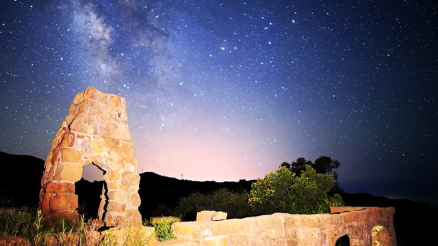  Astrophotography time lapse footage with pan left motion of milky way galaxy spanning over arch-shaped abandoned brick ruin structure at Knapp's Castle in Santa Barbala, California