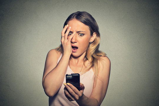 anxious scared young girl looking at phone seeing bad news