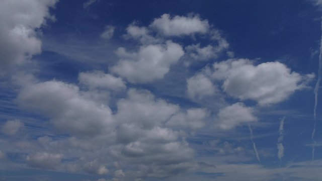 右に飛行機雲が3本あり、上空の雲は上から下に、少し低い位置にある雲は下から上に流れる4Kで撮影したタイムラプス動画です。