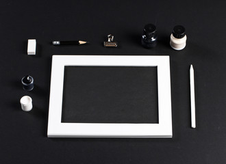 black and white mock up with white wooden photo frame with black field and set of gouache...