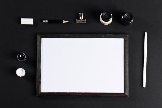 black and white mock up with black wooden photo frame with white field and set of gouache water-colors. Artist painter workplace 