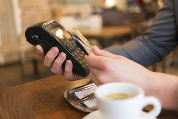 Man using his credit card with NFC technology in a coffee bar