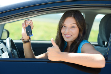 cheerful and happy young woman in car showing car keys