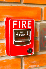 Fire Alarm Switch on the orange brick wall background texture.
