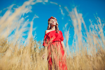 Obraz premium Girl in the Red Dress is Walking on the Field