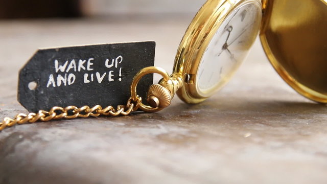 Time to live the idea. "Wake up and live"  inscription on the label and gold pocket watch.