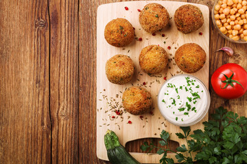 Chickpea falafel balls on a wooden desk with vegetables