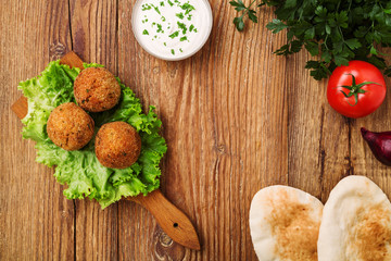 Chickpea falafel balls on a wooden desk with vegetables