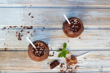 Chocolate and banana smoothie with chocolate balls in jars  on white rustic table 