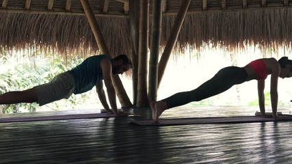 Young couple doing plank exercise in wooden barn 
