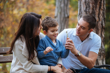 Young happy family enjoy outdoors and sitting on a park bench.