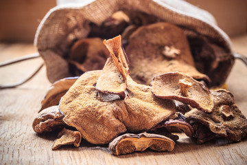 Dry mushrooms in sack on wooden table.