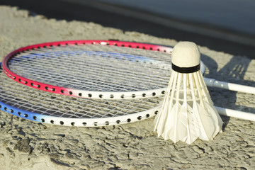 Badminton racquets with shuttlecock on a stone bench against the