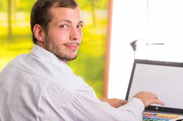 Man working on laptop turning around towards camera