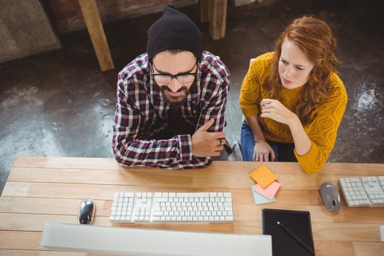 High angle view of colleagues looking at computer 