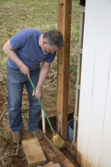 Man wearing blue shirt sweeping dirt with a broom