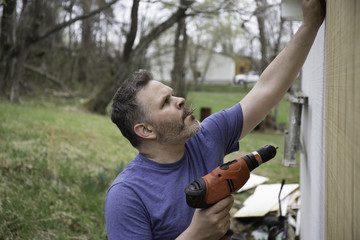 Man working construction job holding drill with nails in his mouth