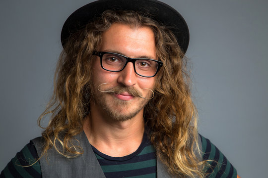 Close up headshot of a hipster modern young man with long hair smiling handlebar mustache