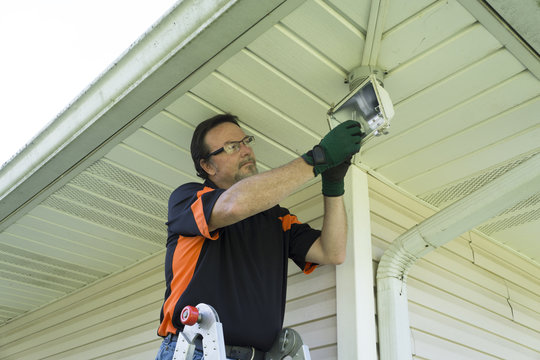 Electrician Taking Defective Bulb Out Of Outside Light Fixture