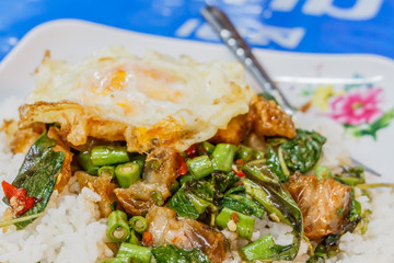 Steamed rice topped with stir-fried crisp pork , basil and over