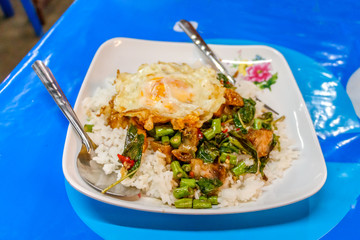 Steamed rice topped with stir-fried crisp pork , basil and over
