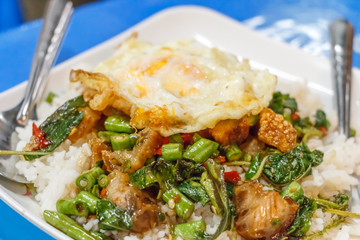 Close up Steamed rice topped with stir-fried crisp pork , basil