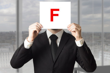 businessman in suit holding up sign with letter f