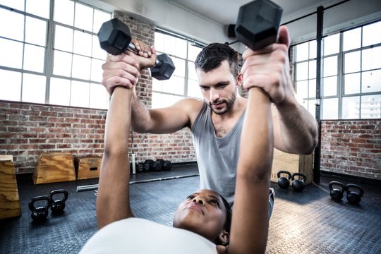 Personal trainer working with client holding dumbbell