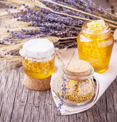 Arrangement of small glass jars with lavender honey, honeycombs and bee pollen