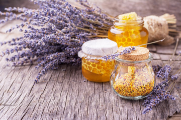 Arrangement of small glass jars with lavender honey, honeycombs and bee pollen