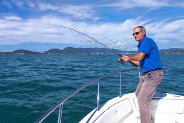 Angler fisherman fighting big fish on the ocean from the boat - 92190138