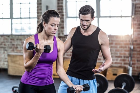  Fit woman lifting dumbbells with trainer