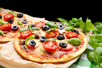 Tasty pizza with vegetables and basil on table close up