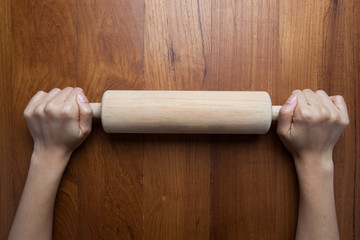 wooden roller,female cook rolling dough with rolling-pin. Closeu