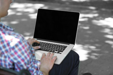 Young man with laptop outdoors
