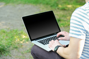 Young man with laptop outdoors