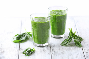 Glasses of spinach juice on wooden table, closeup