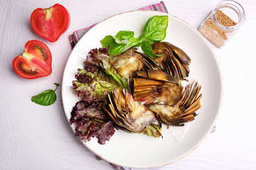 Roasted artichokes on plate, on kitchen table background