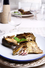 Roasted artichokes on plate, on kitchen table background