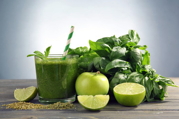 Green healthy juice with fruits and herbs on gray background