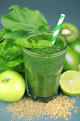 Green healthy juice with fruits and herbs on table close up