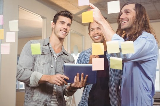 Businessmen smiling while looking at sticky notes