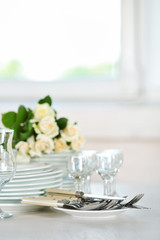 Clean plates, glasses and cutlery on white table