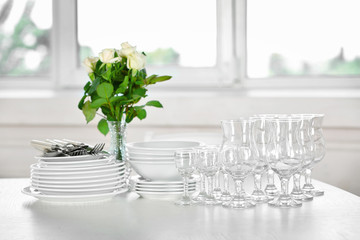 Clean plates, glasses and cutlery on white table