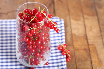 Fresh red currants in glass on table close up