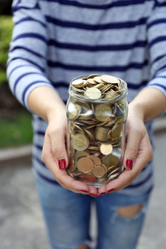 Woman Holding Money Jar With Coins Outdoors