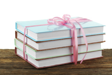 Stack of books with ribbon on light background
