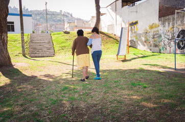 Grandmother and granddaughter walking together holding arms